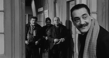 Movie still from “The Organizer” (1963), directed by Mario Monicelli – A group of people standing next to each other in front of a building; Medium shot, Over the shoulder angle
