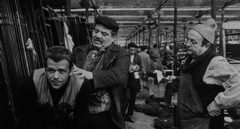 Movie still from “The Organizer” (1963), directed by Mario Monicelli – An old photo of a man cutting another man's hair; Medium shot, Over the shoulder angle