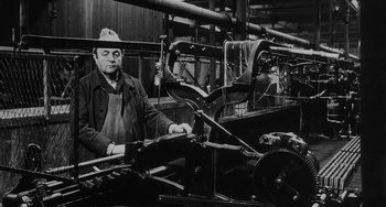 Movie still from “The Organizer” (1963), directed by Mario Monicelli – An older man standing in front of a machine; Medium shot, High angle
