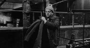 Movie still from “The Organizer” (1963), directed by Mario Monicelli – A black and white photo of a man holding a jacket; Medium shot, High angle