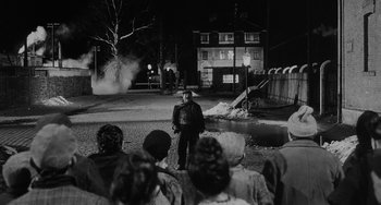 Movie still from “The Organizer” (1963), directed by Mario Monicelli – A group of people standing in the middle of a street at night; Wide shot, Over the shoulder angle