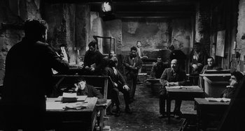 Movie still from “The Organizer” (1963), directed by Mario Monicelli – A black and white photo of a group of men sitting and standing in a room; Wide shot, High angle