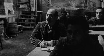 Movie still from “The Organizer” (1963), directed by Mario Monicelli – Black and white photograph of a man sitting at a table; Medium shot, Over the shoulder angle