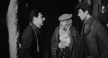 Movie still from “The Organizer” (1963), directed by Mario Monicelli – A group of men standing next to each other on a street; Medium shot, Over the shoulder angle