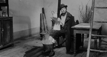 Movie still from “The Organizer” (1963), directed by Mario Monicelli – A man sitting in front of a pot on a stove; Wide shot, High angle
