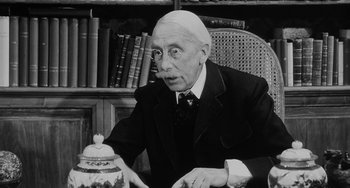 Movie still from “The Organizer” (1963), directed by Mario Monicelli – An older man sitting in a chair in front of a book case; Close Up shot, Over the shoulder angle