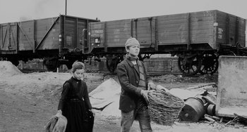 Movie still from “The Organizer” (1963), directed by Mario Monicelli – A man and a boy are standing in front of a train; Wide shot, Low angle
