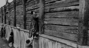Movie still from “The Organizer” (1963), directed by Mario Monicelli – An old photo of a man and a woman climbing up the side of a building; Wide shot, Low angle
