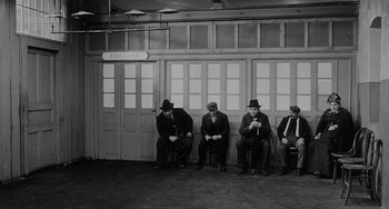 Movie still from “The Organizer” (1963), directed by Mario Monicelli – A black and white photo of a group of men sitting on a bench; Wide shot, High angle