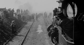 Movie still from “The Organizer” (1963), directed by Mario Monicelli – A group of people standing on train tracks next to a train; Extreme Wide shot, High angle
