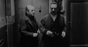 Movie still from “The Organizer” (1963), directed by Mario Monicelli – Two men standing next to each other in front of a door; Medium shot, Low angle