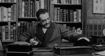 Movie still from “The Organizer” (1963), directed by Mario Monicelli – A man sitting at a table in a library; Medium shot, Low angle