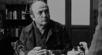 Movie still from “The Organizer” (1963), directed by Mario Monicelli – An older man sitting at a table with a drink in his hand; Close Up shot, Over the shoulder angle