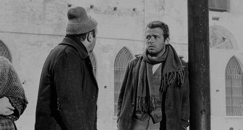 Movie still from “The Organizer” (1963), directed by Mario Monicelli – Two men standing next to each other in front of a building; Medium shot, Over the shoulder angle
