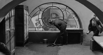 Movie still from “The Organizer” (1963), directed by Mario Monicelli – A black and white photo of a man sweeping the floor; Wide shot, High angle