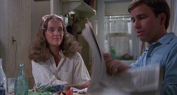 Movie still from “The Other” (1972), directed by Robert Mulligan – A woman sitting at a table reading a newspaper; Medium shot, Over the shoulder angle