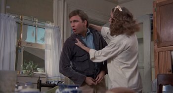 Movie still from “The Other” (1972), directed by Robert Mulligan – A man and a woman are fixing a man's shirt; Medium shot, Over the shoulder angle
