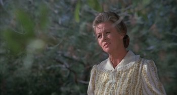 Movie still from “The Other” (1972), directed by Robert Mulligan – An older woman in a yellow dress looks at the camera; Close Up shot, Low angle