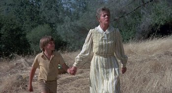 Movie still from “The Other” (1972), directed by Robert Mulligan – An older woman and a young boy holding hands in a field; Medium shot, Low angle