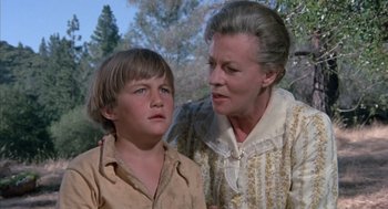 Movie still from “The Other” (1972), directed by Robert Mulligan – An older woman and a young boy standing next to each other in front of trees; Close Up shot, Low angle