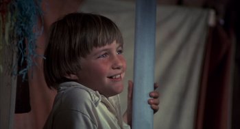 Movie still from “The Other” (1972), directed by Robert Mulligan – A young boy holding onto a large blue object; Close Up shot, Low angle