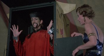 Movie still from “The Other” (1972), directed by Robert Mulligan – A man in a red robe and a black hat is standing in front of another man in a red robe; Medium shot, Low angle