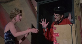 Movie still from “The Other” (1972), directed by Robert Mulligan – A man in a red jacket and a woman in a black hat; Medium shot, Low angle