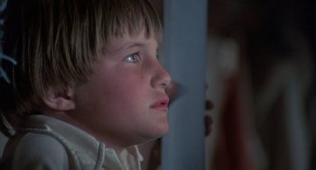 Movie still from “The Other” (1972), directed by Robert Mulligan – A young boy with blue eyes looking out a window; Close Up shot, Low angle
