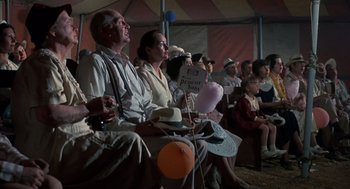 Movie still from “The Other” (1972), directed by Robert Mulligan – A group of people sitting in front of an audience; Wide shot, Low angle