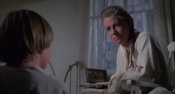 Movie still from “The Other” (1972), directed by Robert Mulligan – An older woman looking in the mirror while a young boy looks on; Close Up shot, Over the shoulder angle
