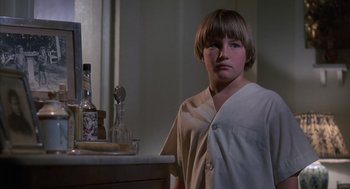 Movie still from “The Other” (1972), directed by Robert Mulligan – A young boy standing in front of a counter; Close Up shot, Low angle