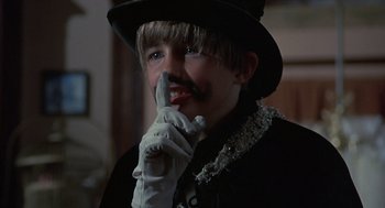 Movie still from “The Other” (1972), directed by Robert Mulligan – A young man wearing a top hat and a white glove; Close Up shot, Over the shoulder angle