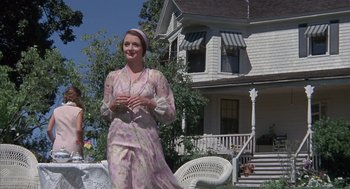 Movie still from “The Other” (1972), directed by Robert Mulligan – A woman standing in front of a white house; Medium shot, Low angle