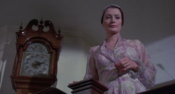 Movie still from “The Other” (1972), directed by Robert Mulligan – A woman standing in front of a grandfather clock; Medium shot, Low angle