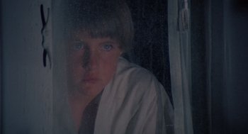 Movie still from “The Other” (1972), directed by Robert Mulligan – A young man looking out of a window at night; Close Up shot, Low angle