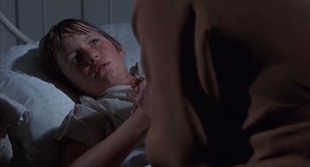 Movie still from “The Other” (1972), directed by Robert Mulligan – A young girl laying in a bed with a dog; Close Up shot, Over the shoulder angle