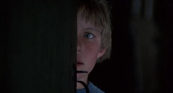 Movie still from “The Other” (1972), directed by Robert Mulligan – A young boy is looking through a hole in the wall; Close Up shot, Low angle