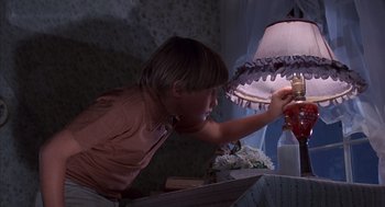 Movie still from “The Other” (1972), directed by Robert Mulligan – A young boy is looking at a lamp in the dark; Close Up shot, High angle