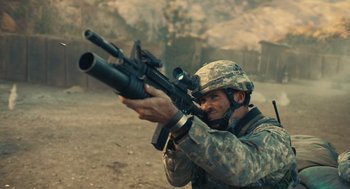 Movie still from “The Outpost” (2019), directed by Rod Lurie – A man in a military uniform is holding a gun; Medium shot, Over the shoulder angle