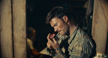 Movie still from “The Outpost” (2019), directed by Rod Lurie – A man in a military fatigues holding a cell phone to his ear; Close Up shot, Over the shoulder angle