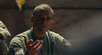 Movie still from “The Outpost” (2019), directed by Rod Lurie – A man with a shaved head talking to someone; Close Up shot, Over the shoulder angle
