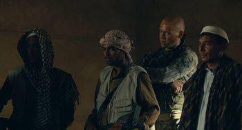 Movie still from “The Outpost” (2019), directed by Rod Lurie – A group of men standing next to each other in a room; Medium shot, Over the shoulder angle