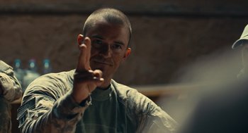 Movie still from “The Outpost” (2019), directed by Rod Lurie – A man with a shaved head is making a peace sign with his hand; Close Up shot, Over the shoulder angle