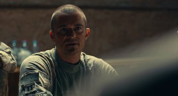 Movie still from “The Outpost” (2019), directed by Rod Lurie – A man sitting in front of a wall looking at the camera; Close Up shot, Over the shoulder angle