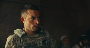 Movie still from “The Outpost” (2019), directed by Rod Lurie – A man in a military uniform is looking at the camera; Medium shot, Over the shoulder angle