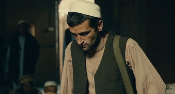 Movie still from “The Outpost” (2019), directed by Rod Lurie – A man wearing a white hat is looking down at the ground; Medium shot, Low angle
