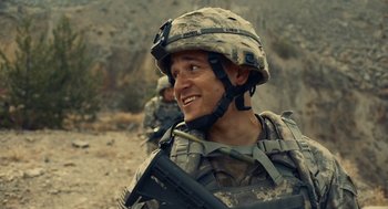 Movie still from “The Outpost” (2019), directed by Rod Lurie – A man in a military uniform is smiling for the camera; Close Up shot, Over the shoulder angle