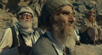 Movie still from “The Outpost” (2019), directed by Rod Lurie – A man with a long beard wearing a hat and glasses; Close Up shot, Low angle