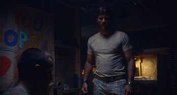 Movie still from “The Outpost” (2019), directed by Rod Lurie – A man standing in a room wearing a tan shirt; Medium shot, Low angle