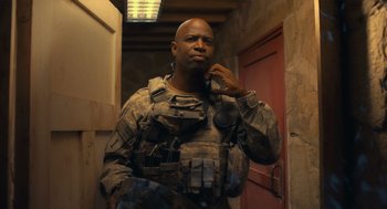 Movie still from “The Outpost” (2019), directed by Rod Lurie – A man in military fatigues standing next to a door; Medium shot, Over the shoulder angle